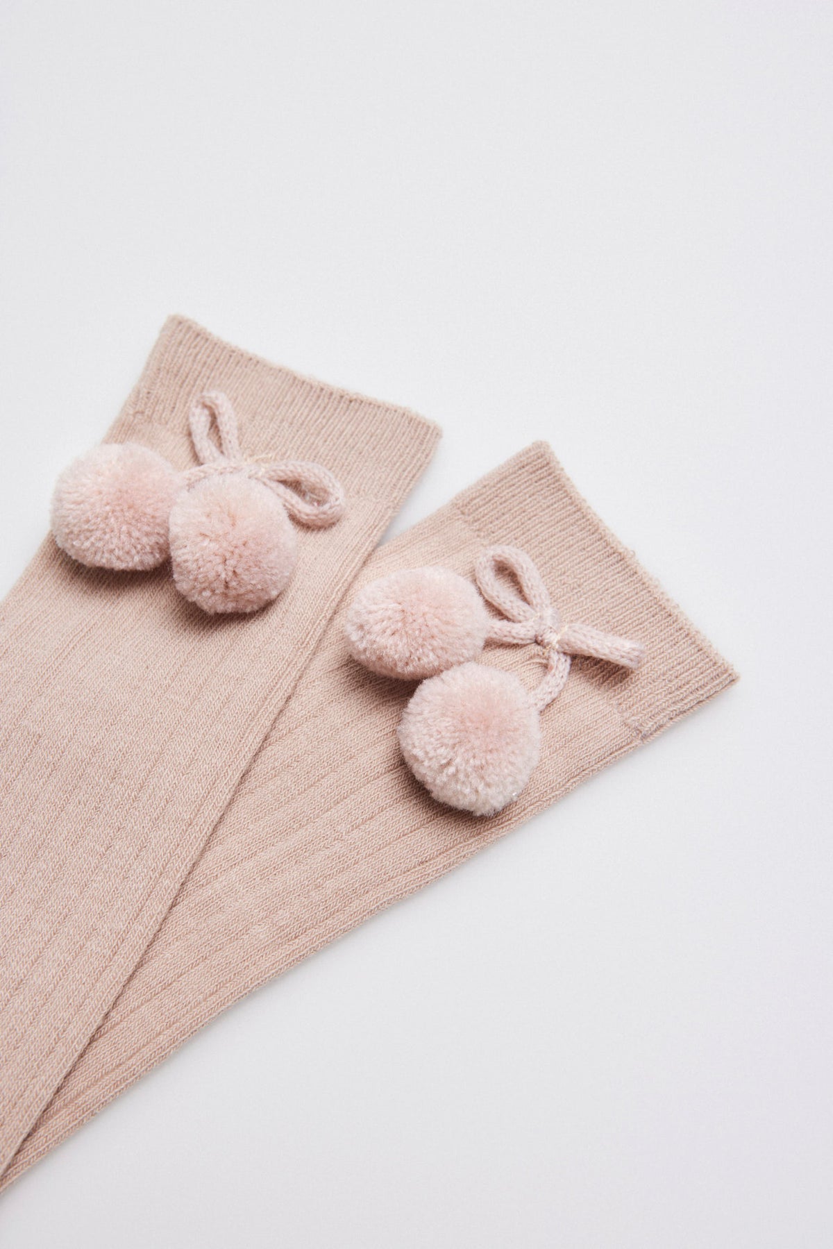 Meias altas infantis bege com detalhes de pompons