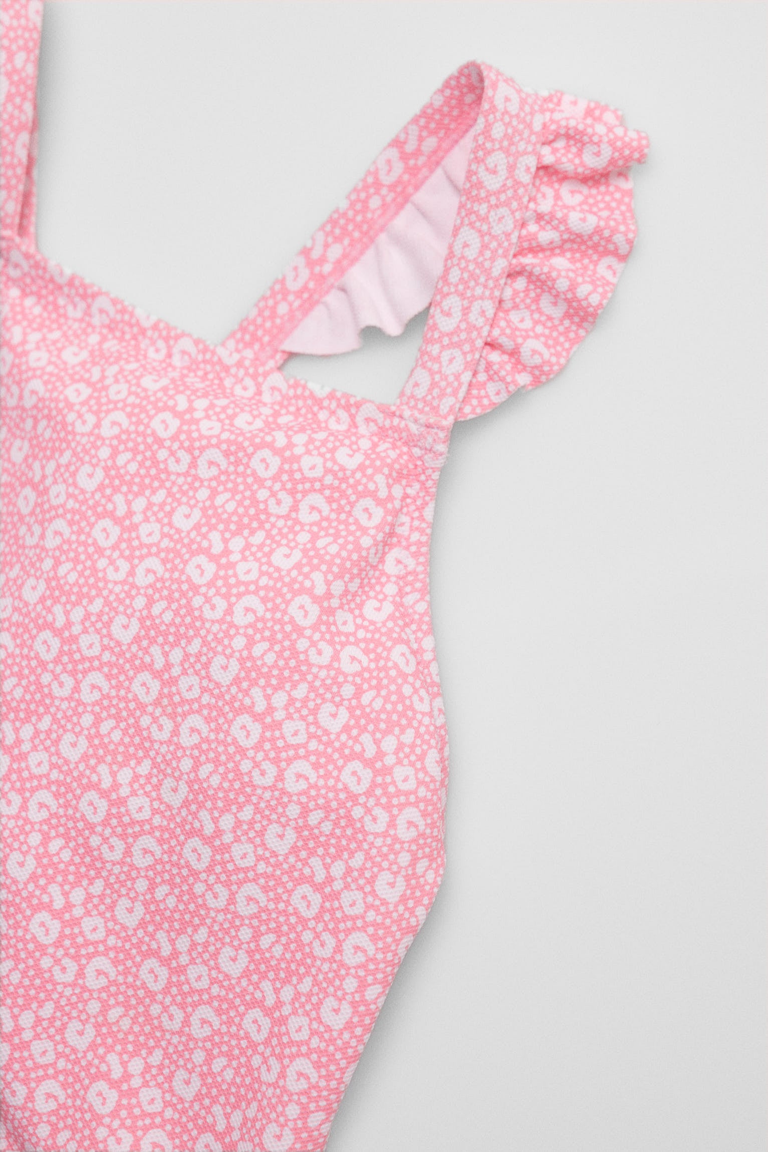Maiô infantil com detalhes de babados e alças cruzadas, estampa de leopardo rosa.