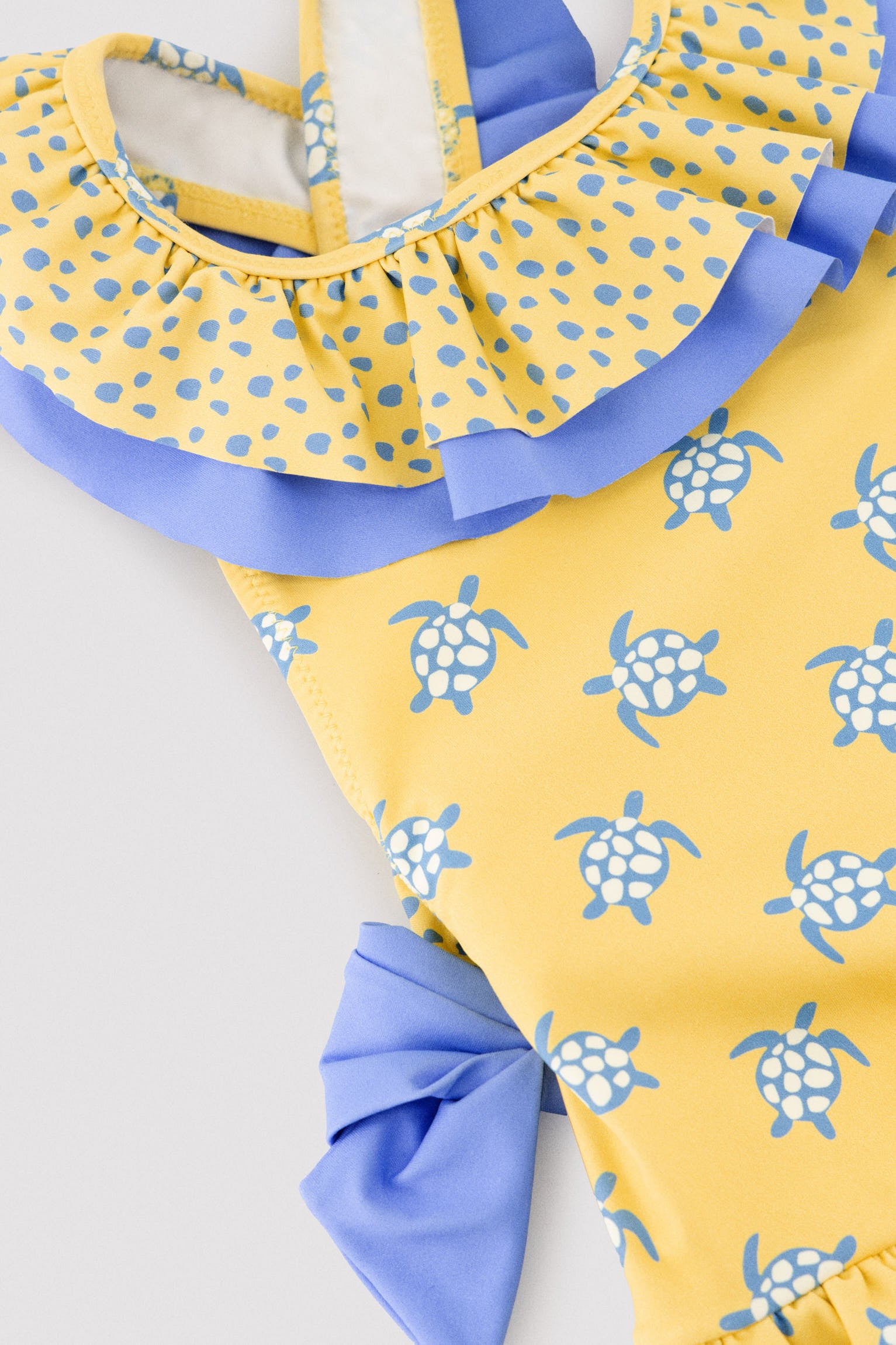 Maiô infantil com detalhes de babados e laços, estampa de tartaruga.