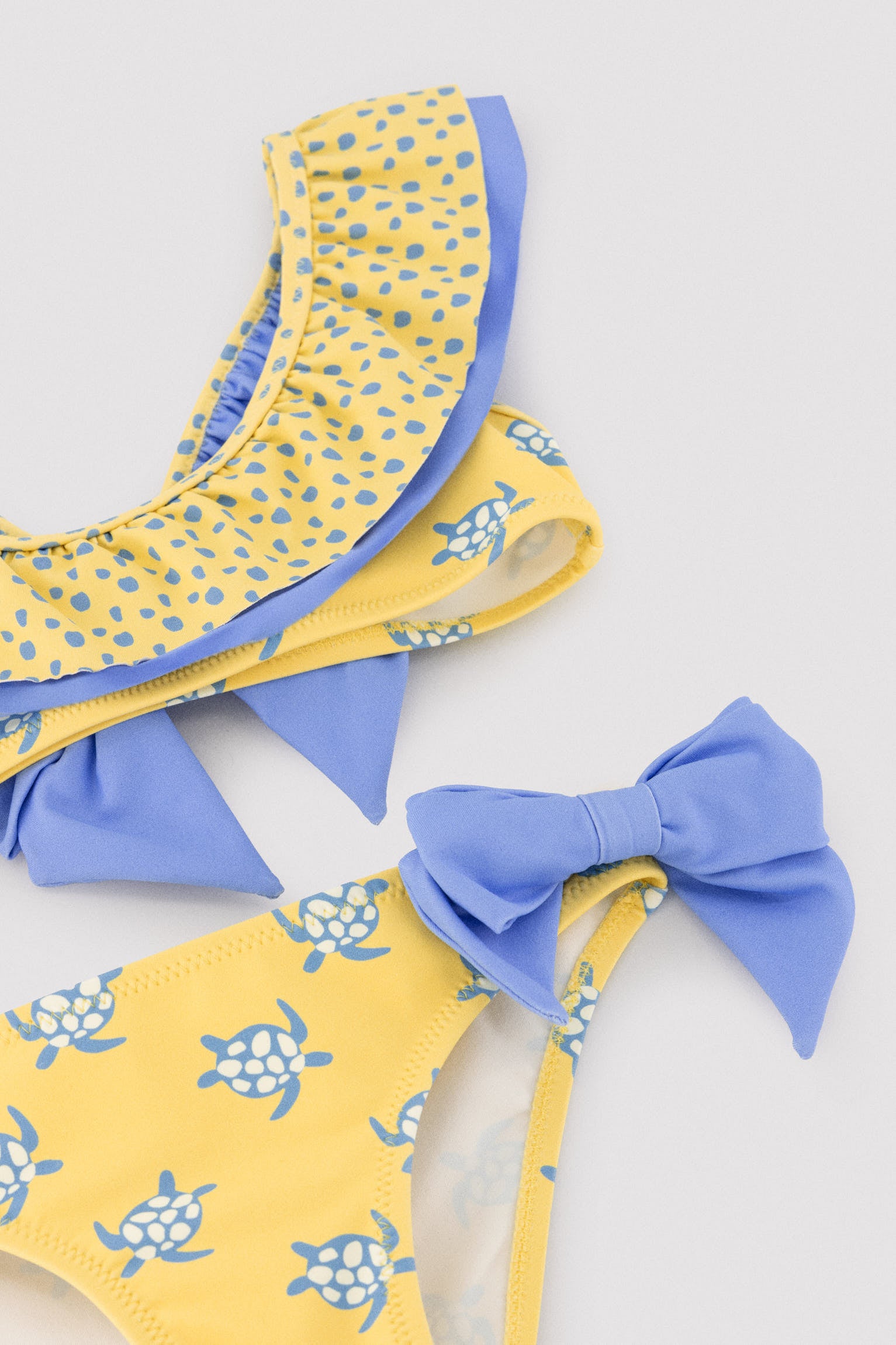 Biquíni infantil com detalhe de babados e laços, estampa de tartaruga.