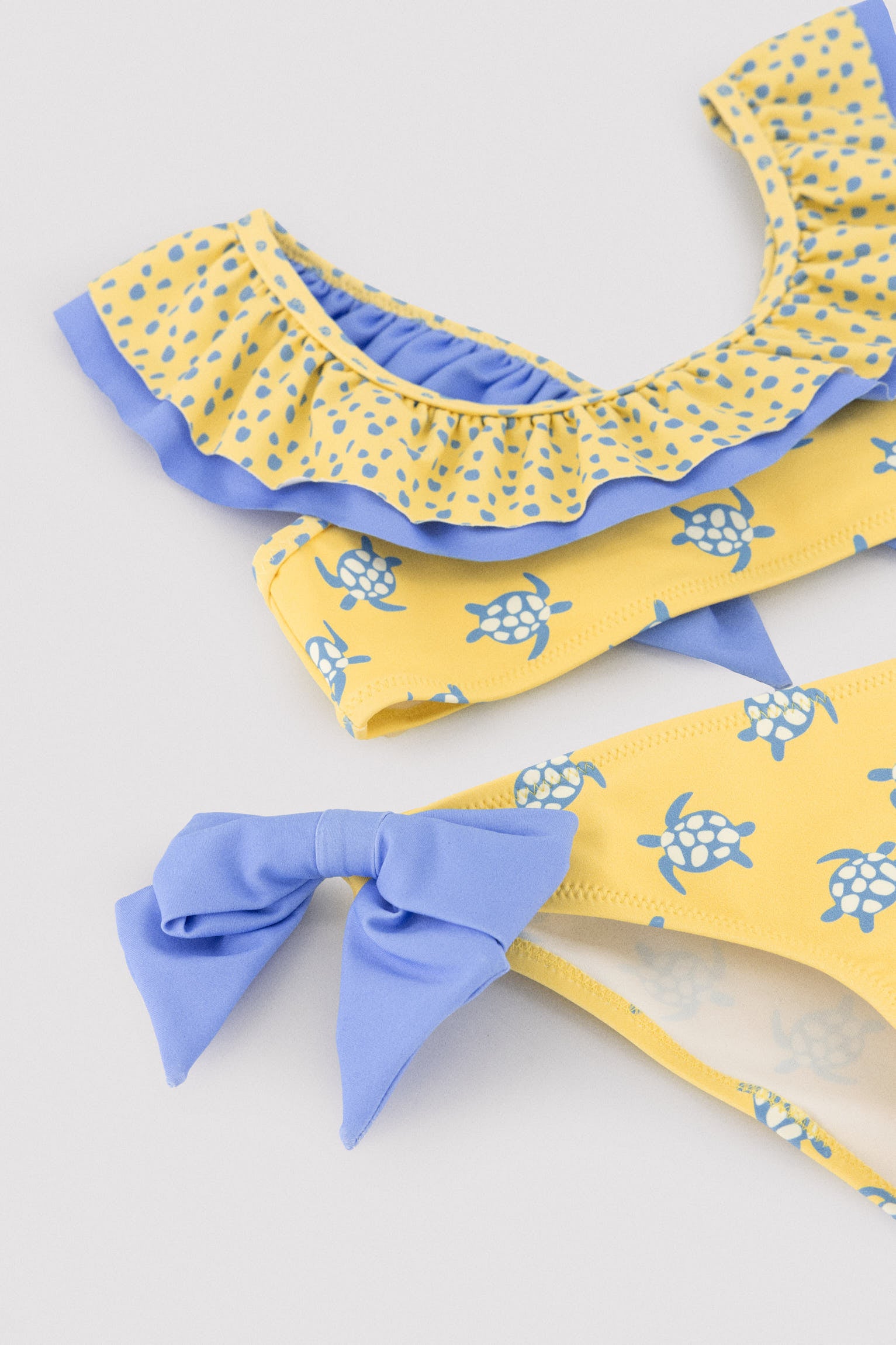 Biquíni infantil com detalhe de babados e laços, estampa de tartaruga.