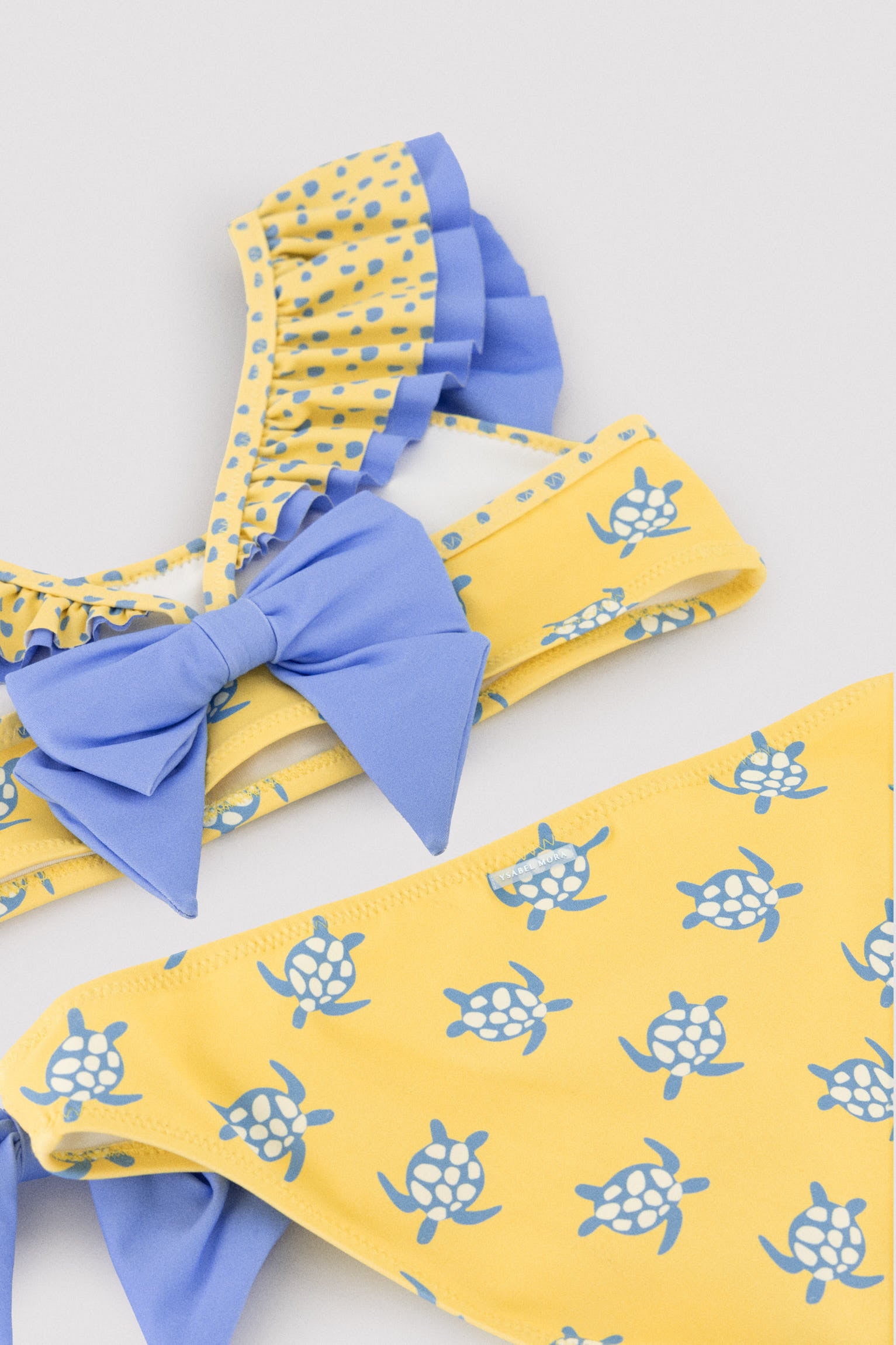 Biquíni infantil com detalhe de babados e laços, estampa de tartaruga.