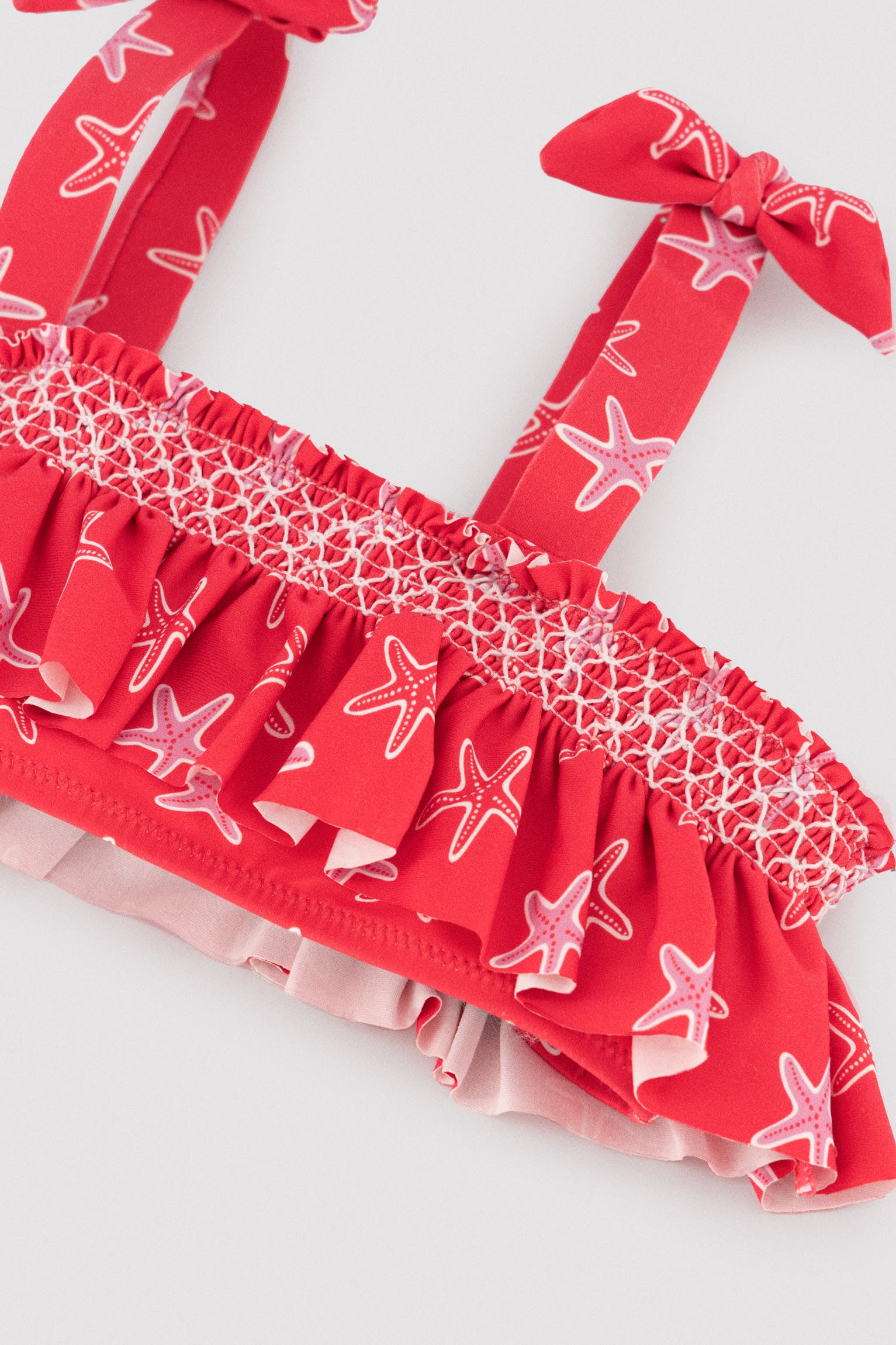 Biquíni infantil com detalhes em babados e estampa de favo de mel com estrelas-do-mar.