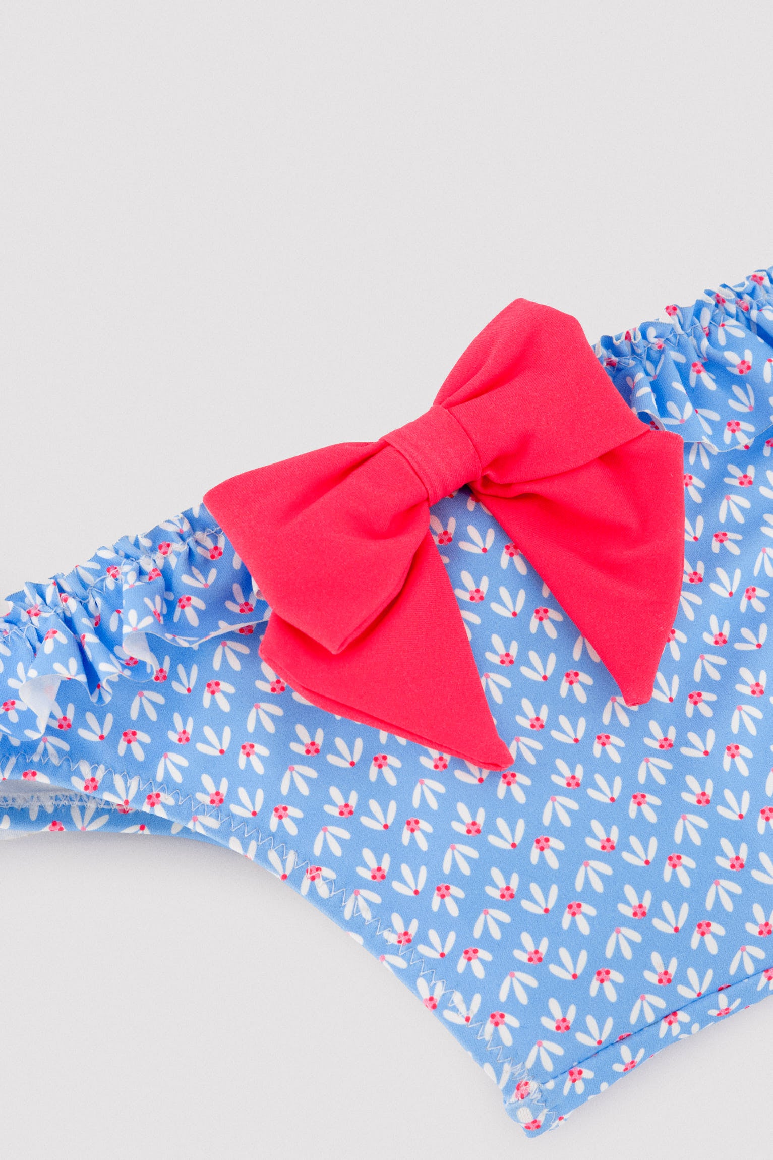 Calcinhas de bebê com detalhes de babados e laços, estampa floral.