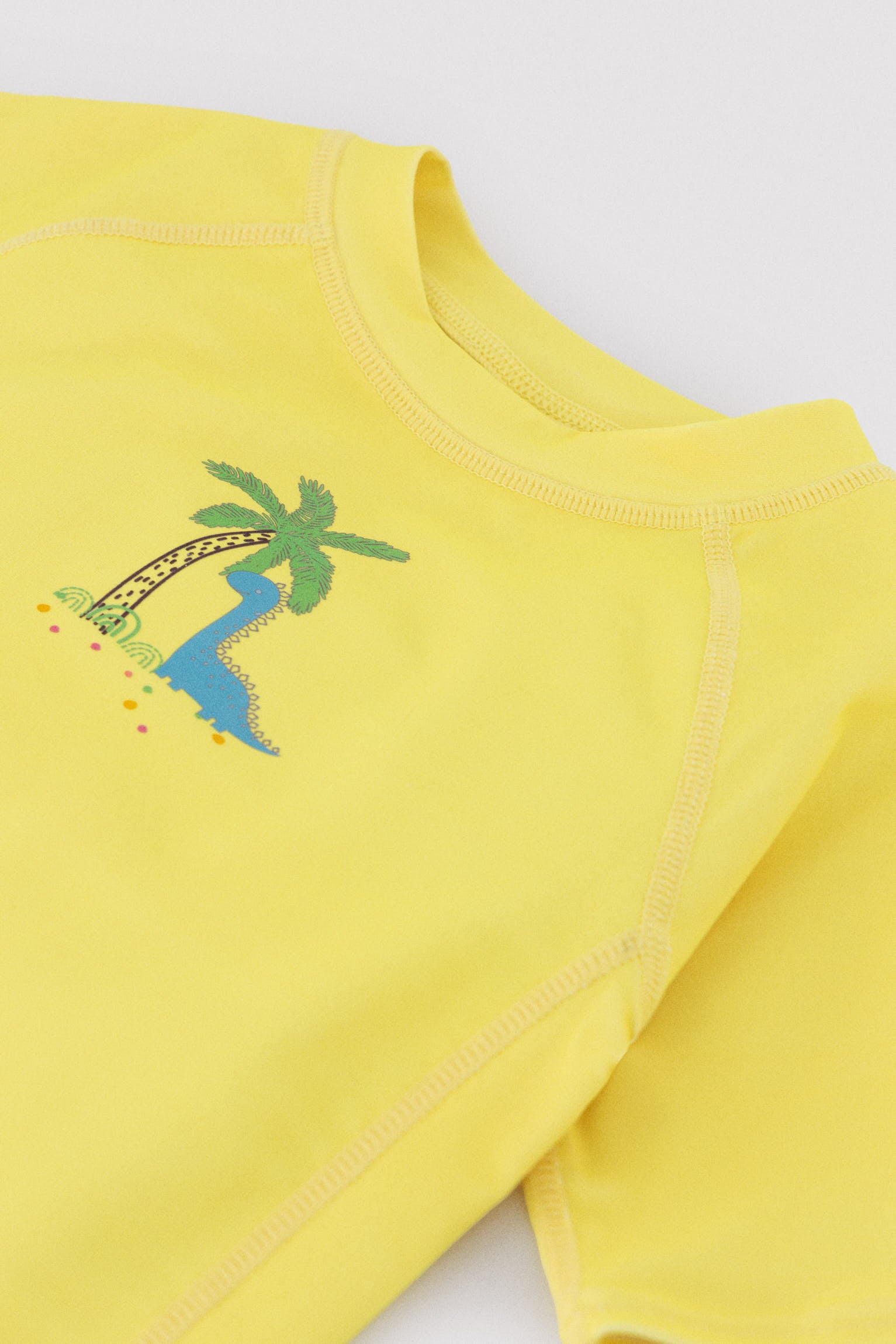 Camiseta de banho infantil com estampa de dinossauro e palmeira