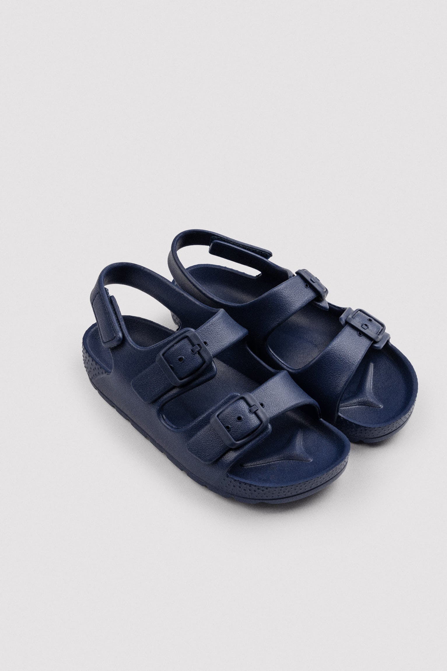 Chinelo infantil com fivelas ajustáveis ​​e velcro azul-marinho.
