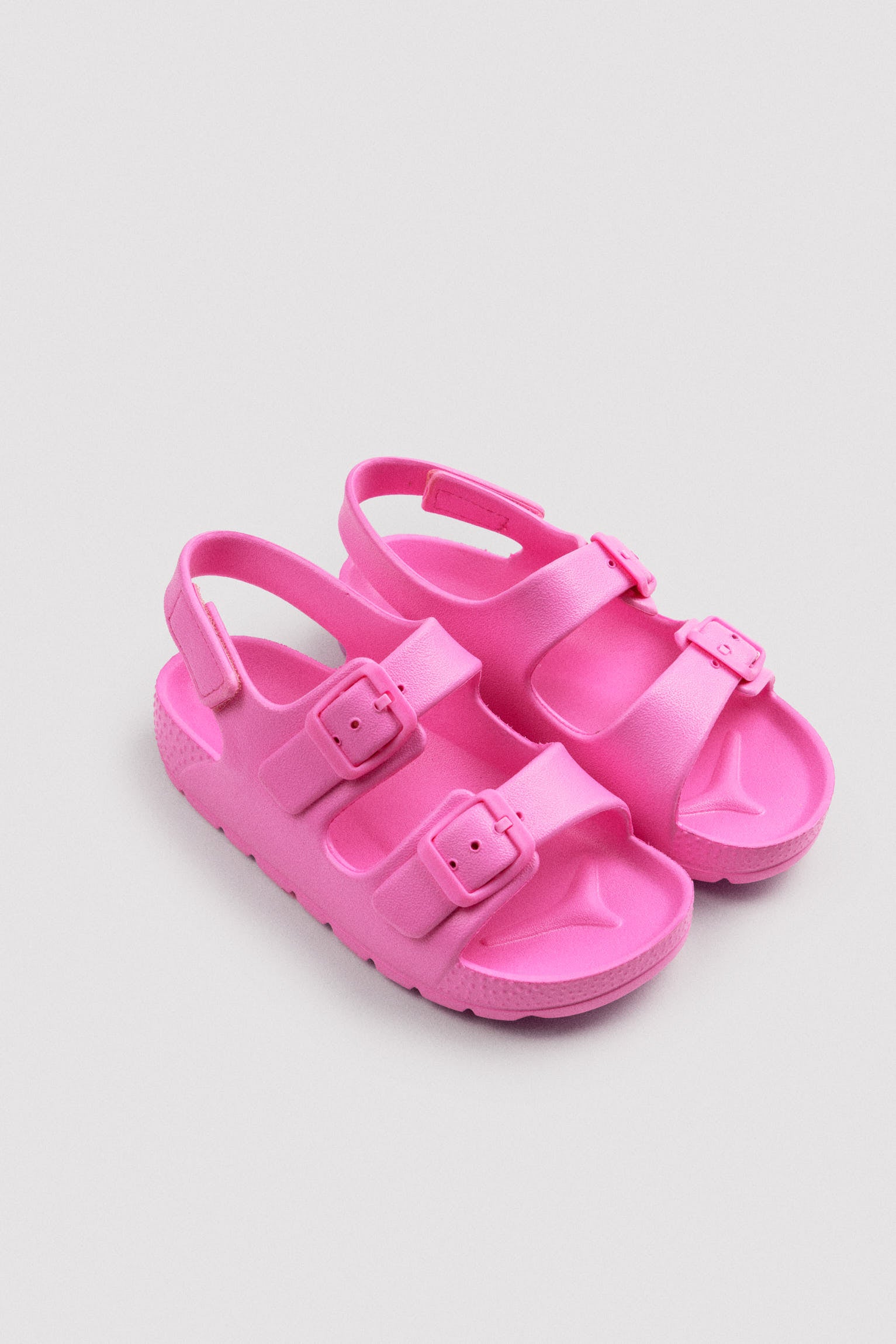 Chinelo infantil rosa com fivelas ajustáveis ​​e fecho de velcro.